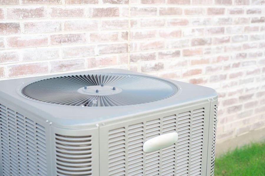 Outdoor central air conditioner with brick siding from house behind it