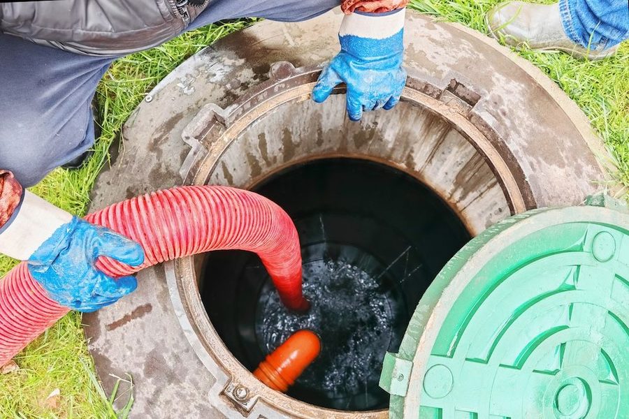 Plumbers working on repairing a sewer in a yard. Water is draining into the sewer.