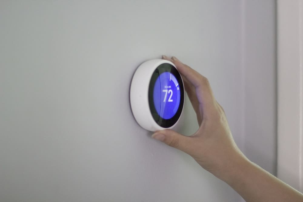 Homeowner adjusting smart thermostat on the wall displaying 72 degrees